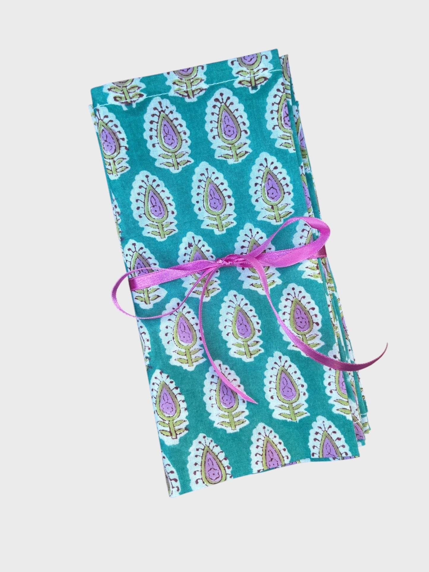 A set of 4 teal block printed napkins with floral design. Tied with ribbon