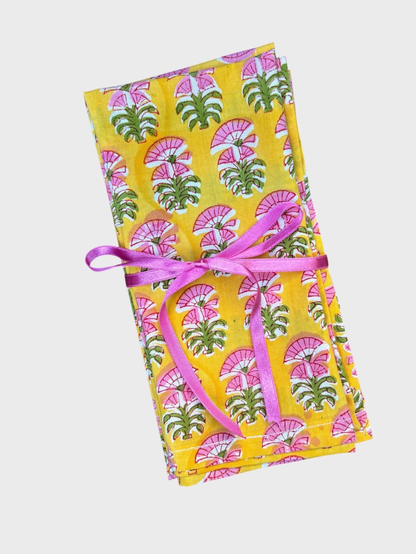 A set of yellow block printed napkins with a pink flower