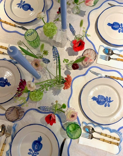 A blue and white table setting with fresh flowers and sky blue candles
