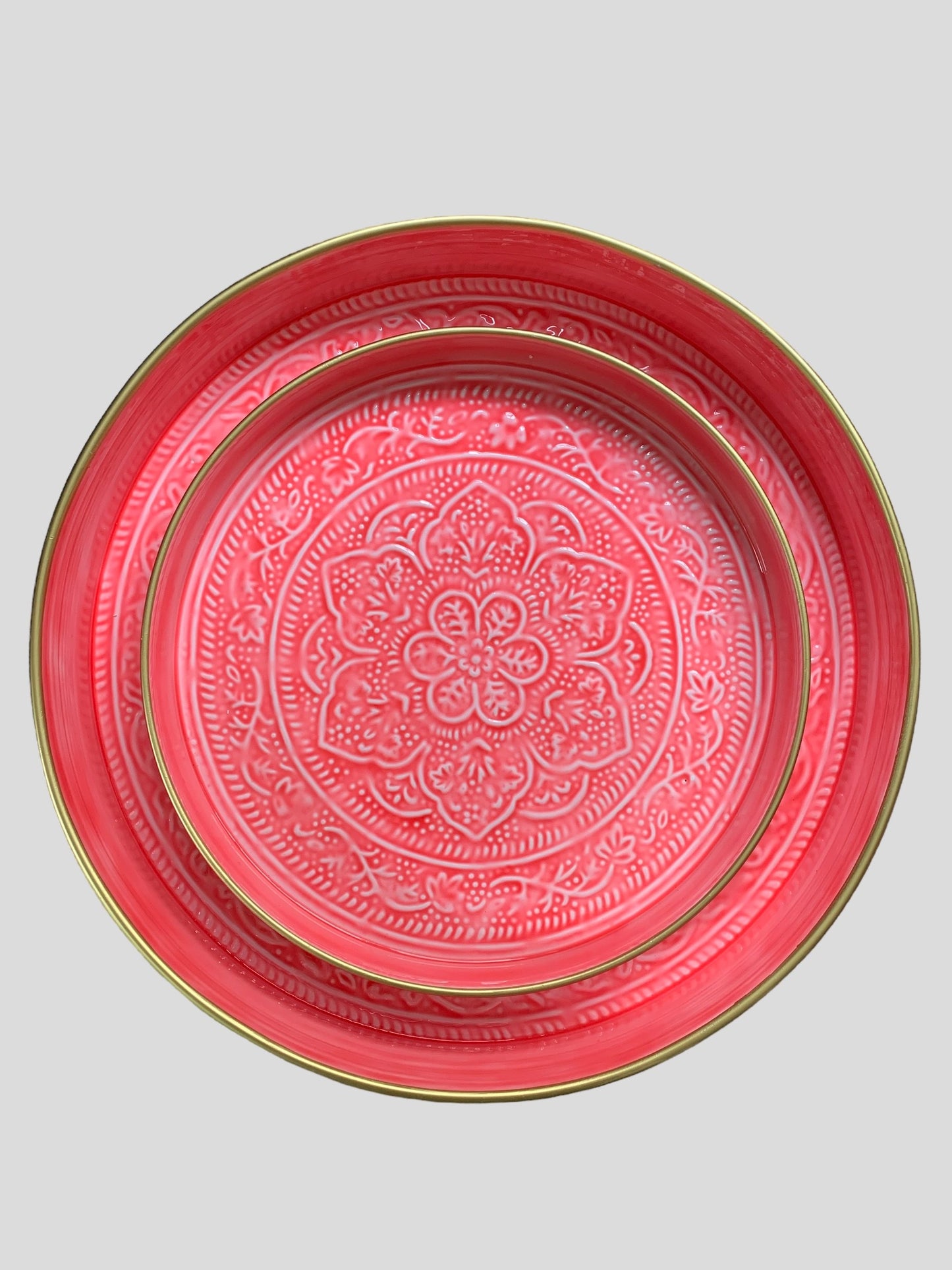 A nest of bright pink enamel trays with a floral pattern.