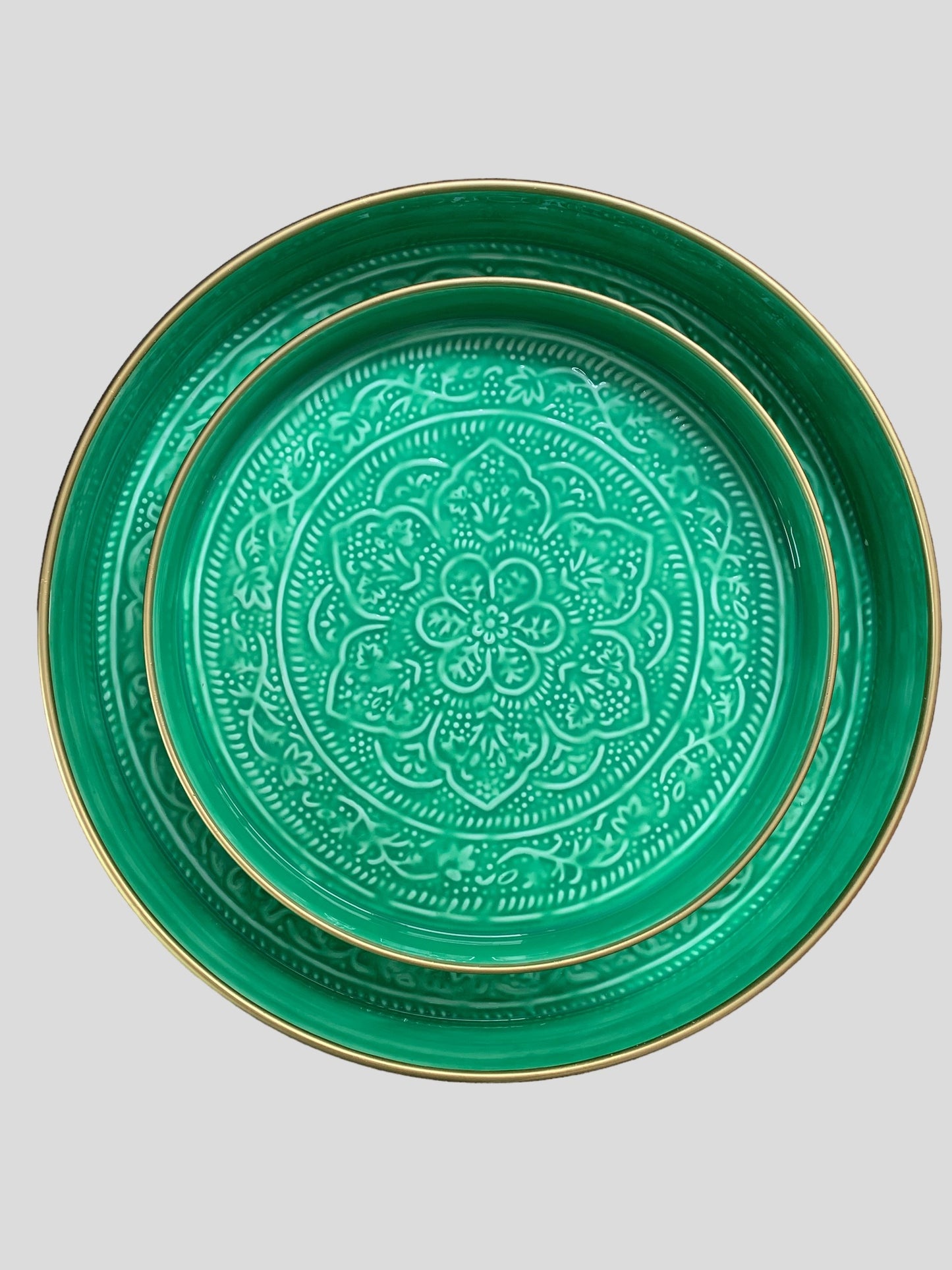 A medium sized bright green enamel tray sitting inside a larger green enamel tray. The trays have been embossed with a floral pattern.