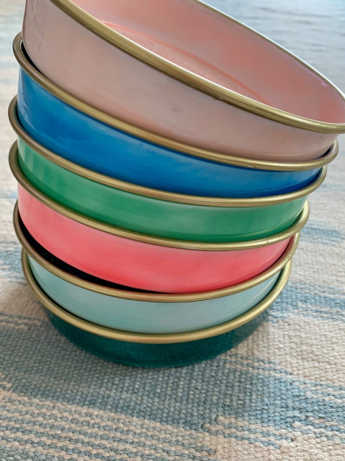 6 colourful enamel trays in rainbow colours all stacked together.