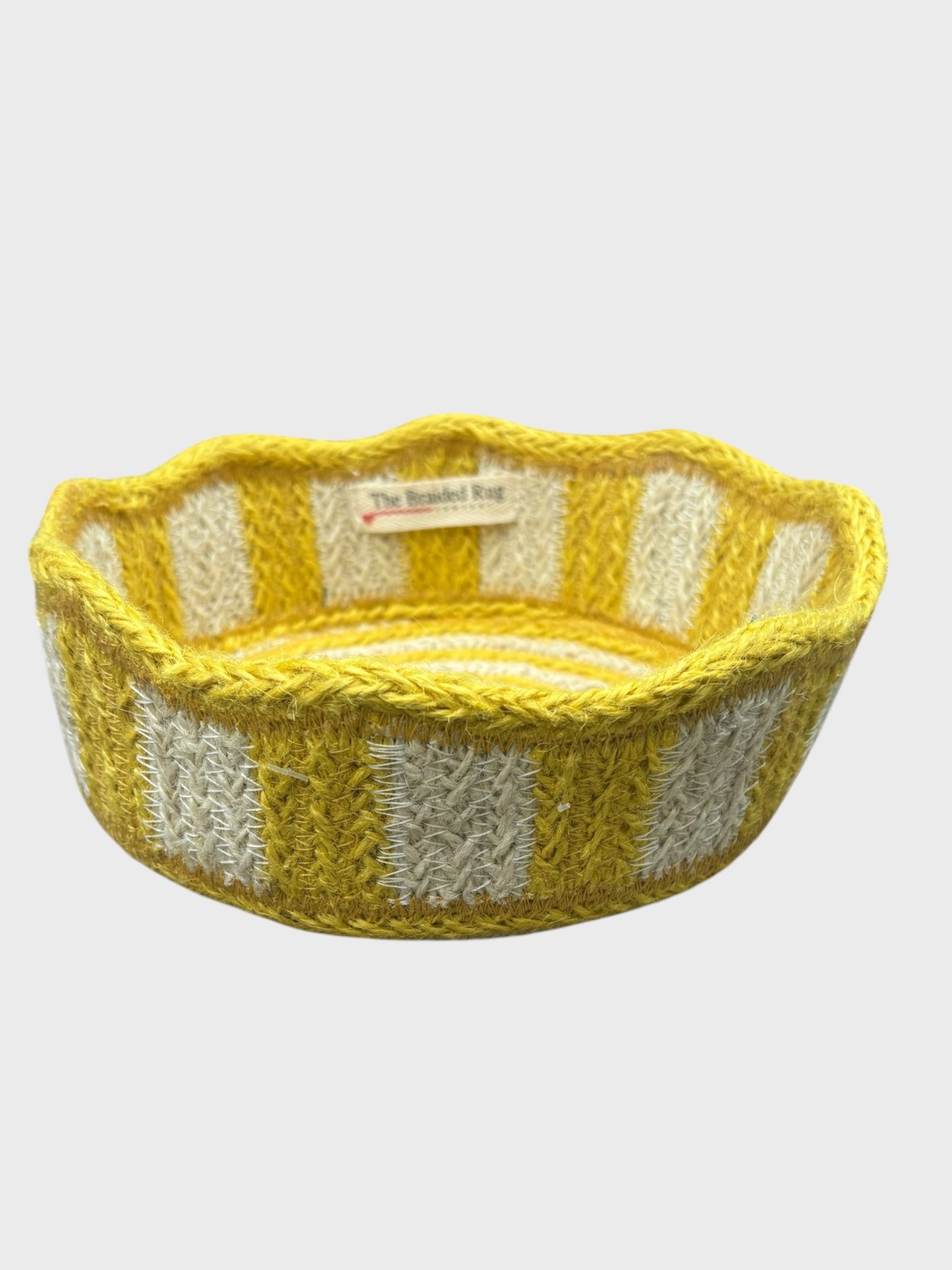 A yellow striped mini jute basket with scalloped edging