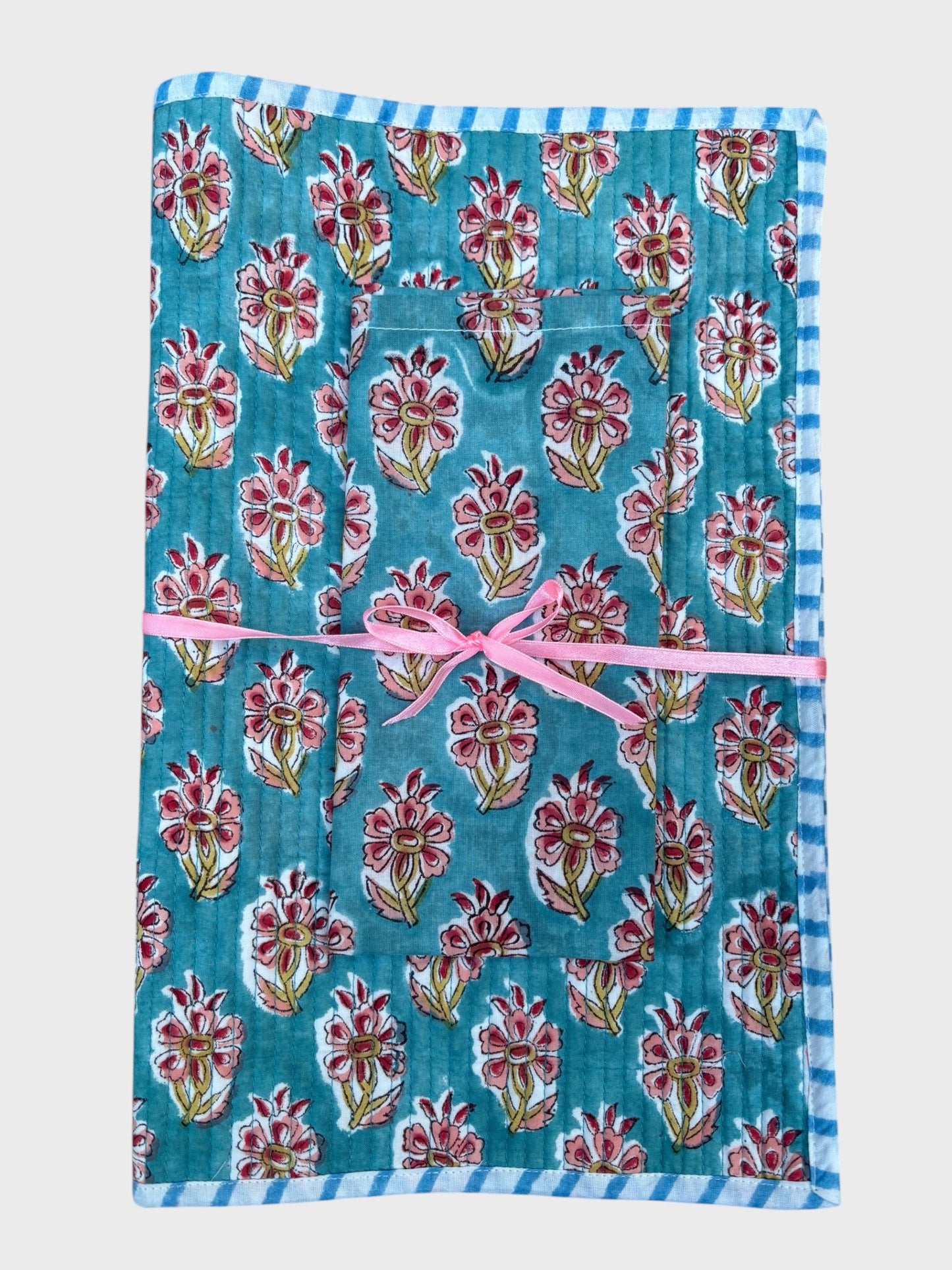 A block printed placemat and napkin set. Blue background with a pink hibiscus flower design.
