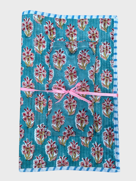 A block printed placemat and napkin set.  Blue background with a pink hibiscus flower design.