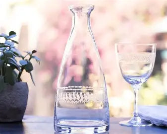 Clear glass carafe and wine glass on a blurred outdoor background