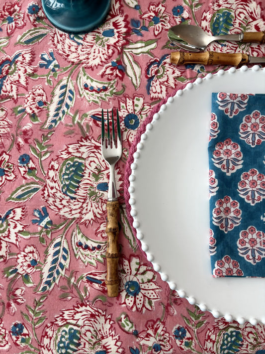 Table setting with floral tablecloth, white plate, fork, and napkin.