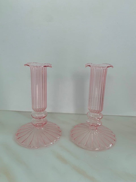 A pair of short, pink glass candleholders with a ribbed design and a fluted top.