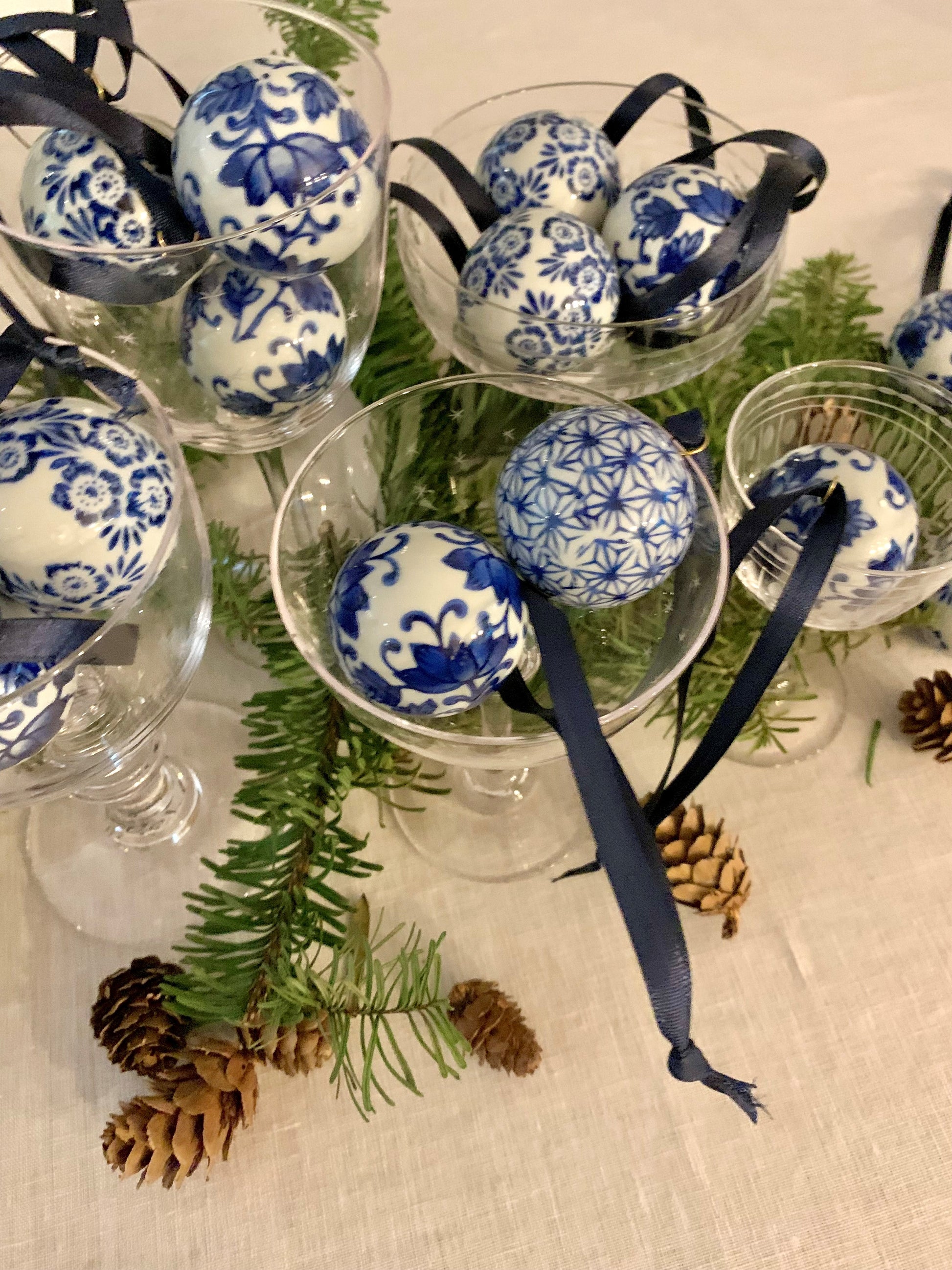mini blue and white ceamic baubles in champagne coupes surrounded by christmas greenery