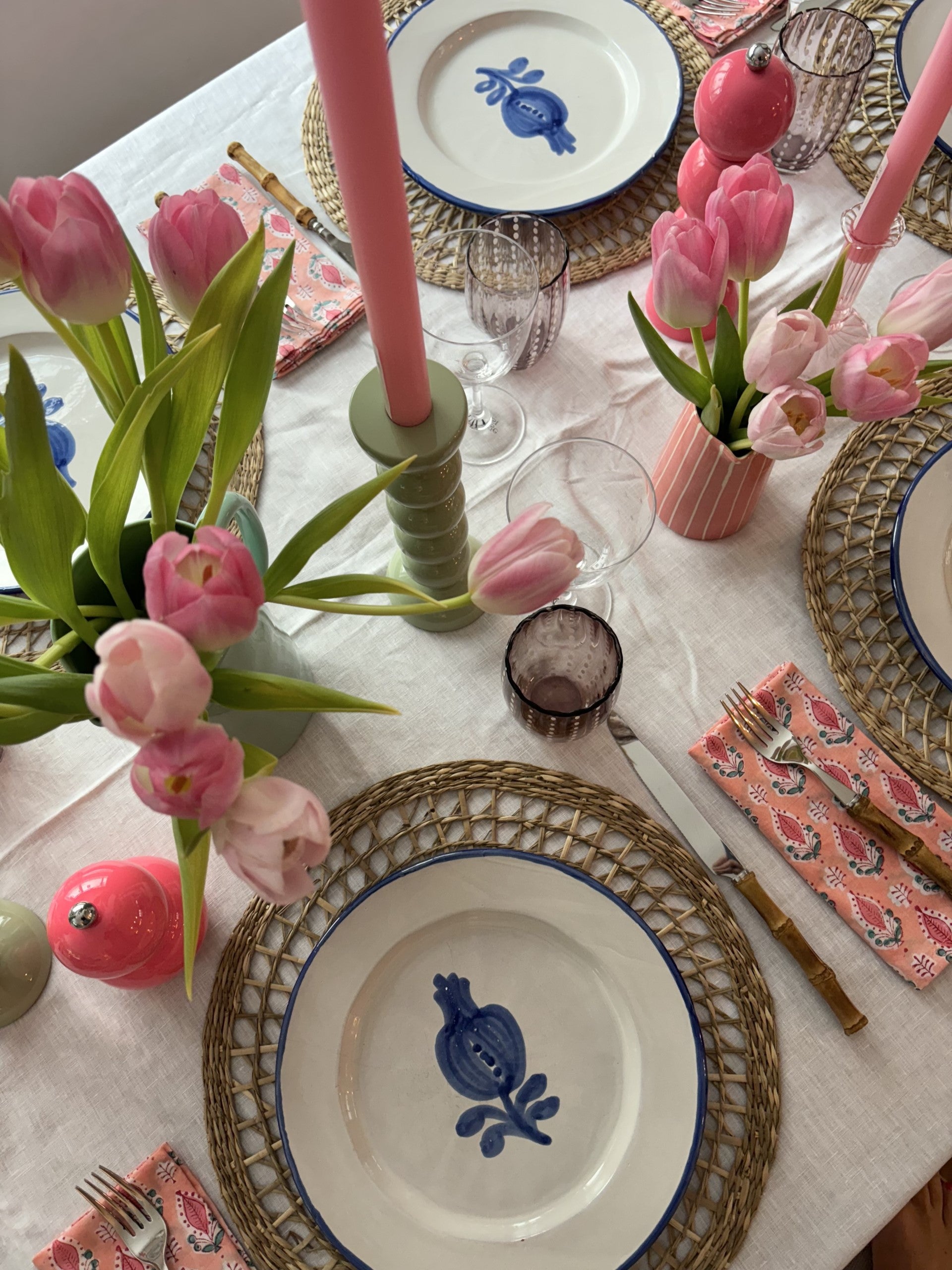 A pink table setting for Valentine's Day with fresh pink tulips in vases and pink block printed napkins.