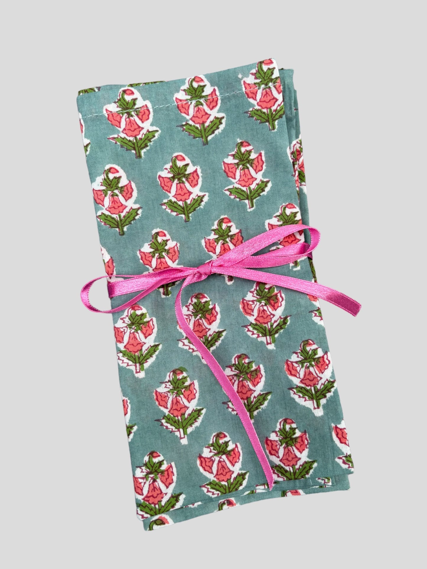 A set of blue and pink floral block print napkins tied with pink ribbon.