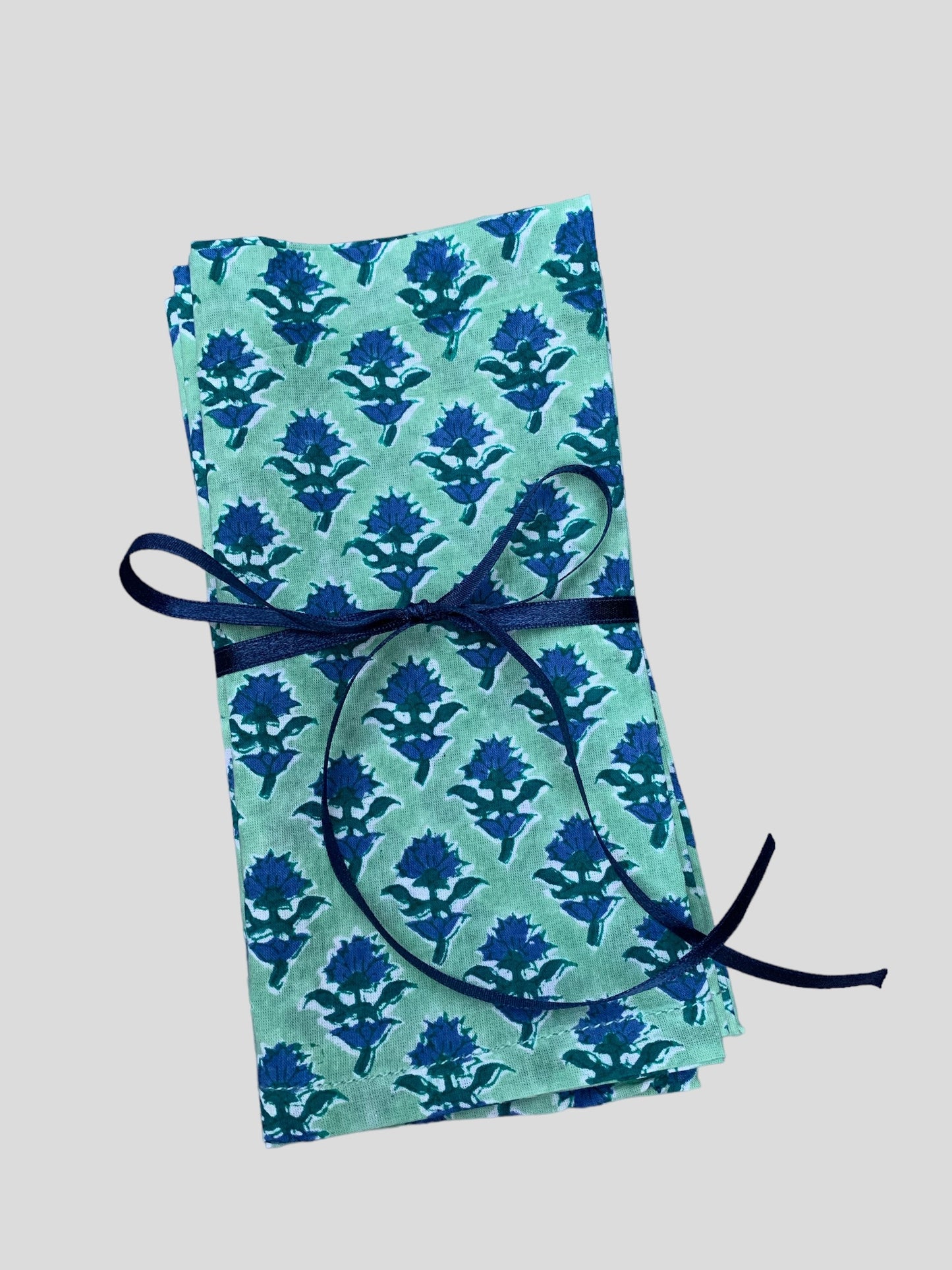 A set of 4 block printed napkins with a blue and green thistle design.  Tied with a blue ribbon.