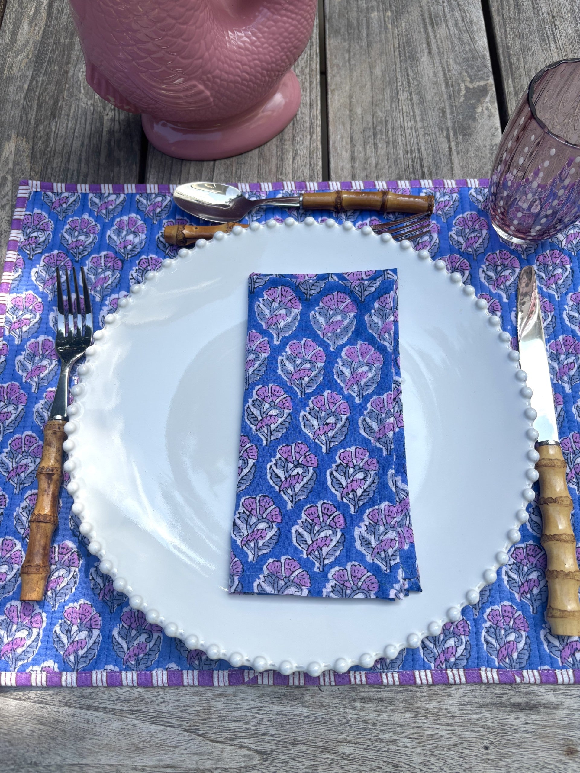 Dinner setting with a blue patterned napkin on a white plate, placed on a wooden table.