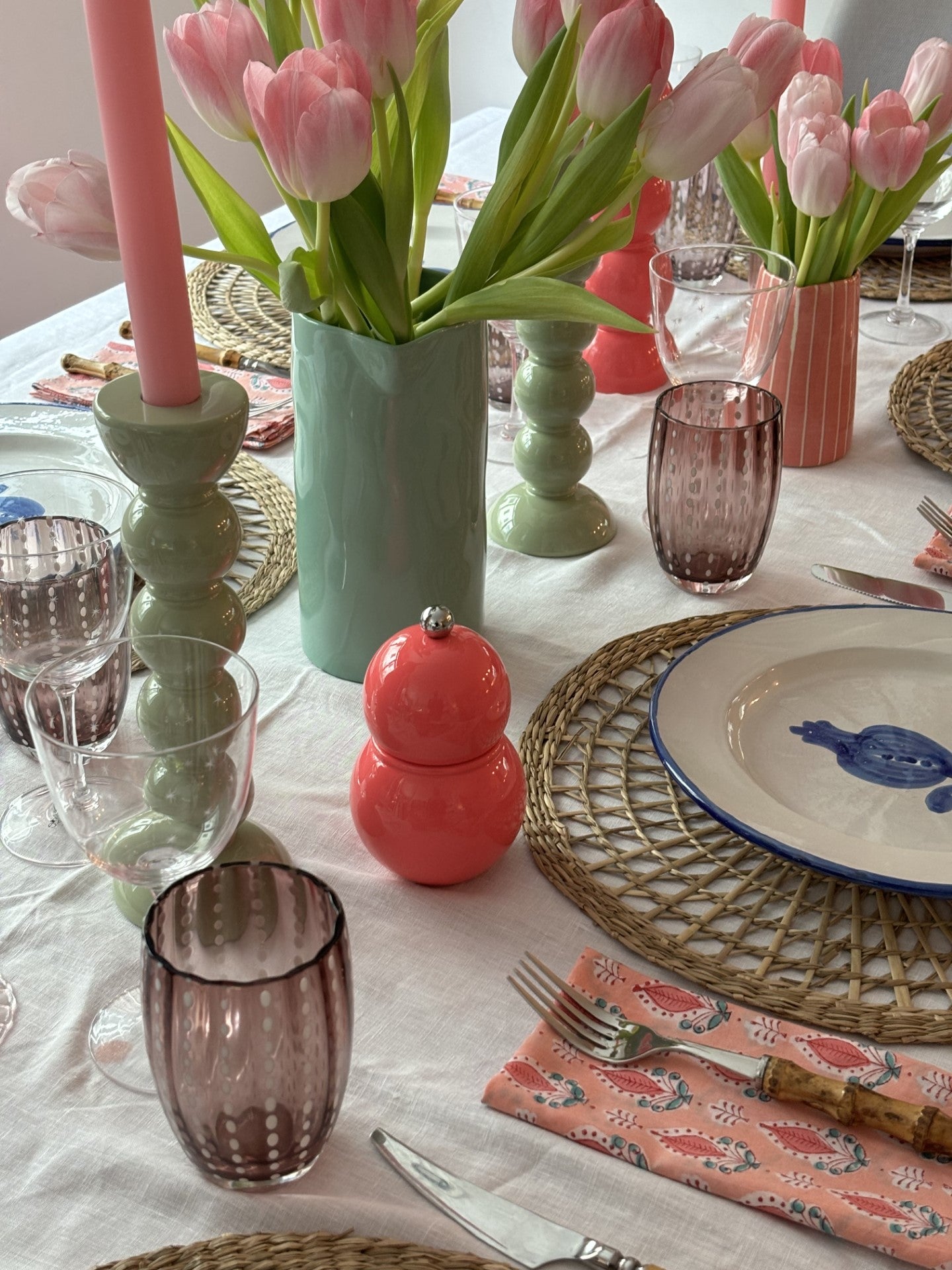 A pink and green table setting with fresh tulips and sage bobbin candlestick with rose candles.