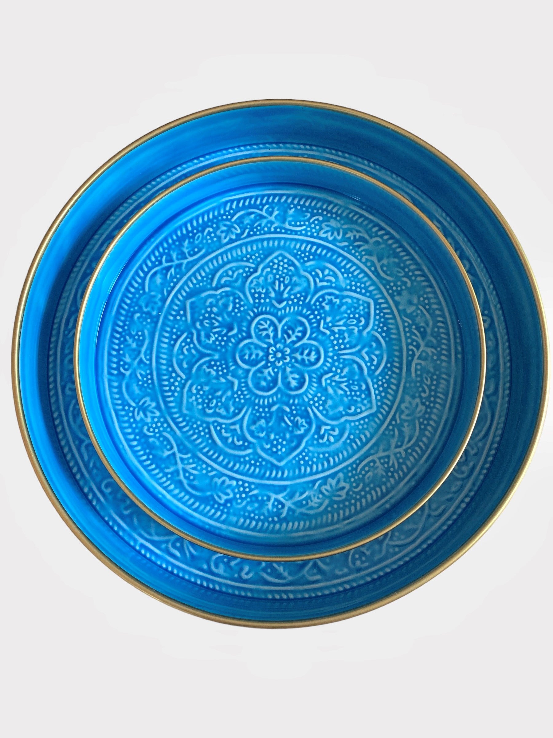 A nest of bright blue enamel trays with floral embossed detail.