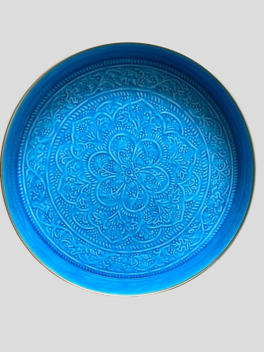 A large, round, blue enamel serving tray with embossed detail