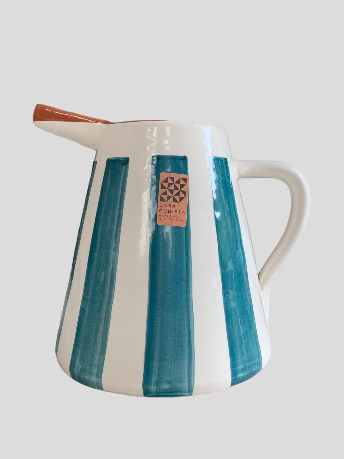 A large ceramic jug hand-painted with bold stripes in teal.  Made in Portugal by casa cubista