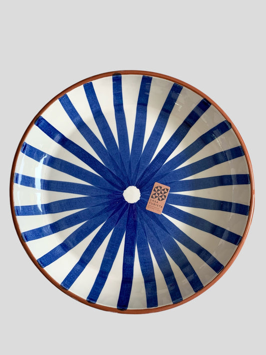 A large ceramic platter with a hand-painted ray design in blue.