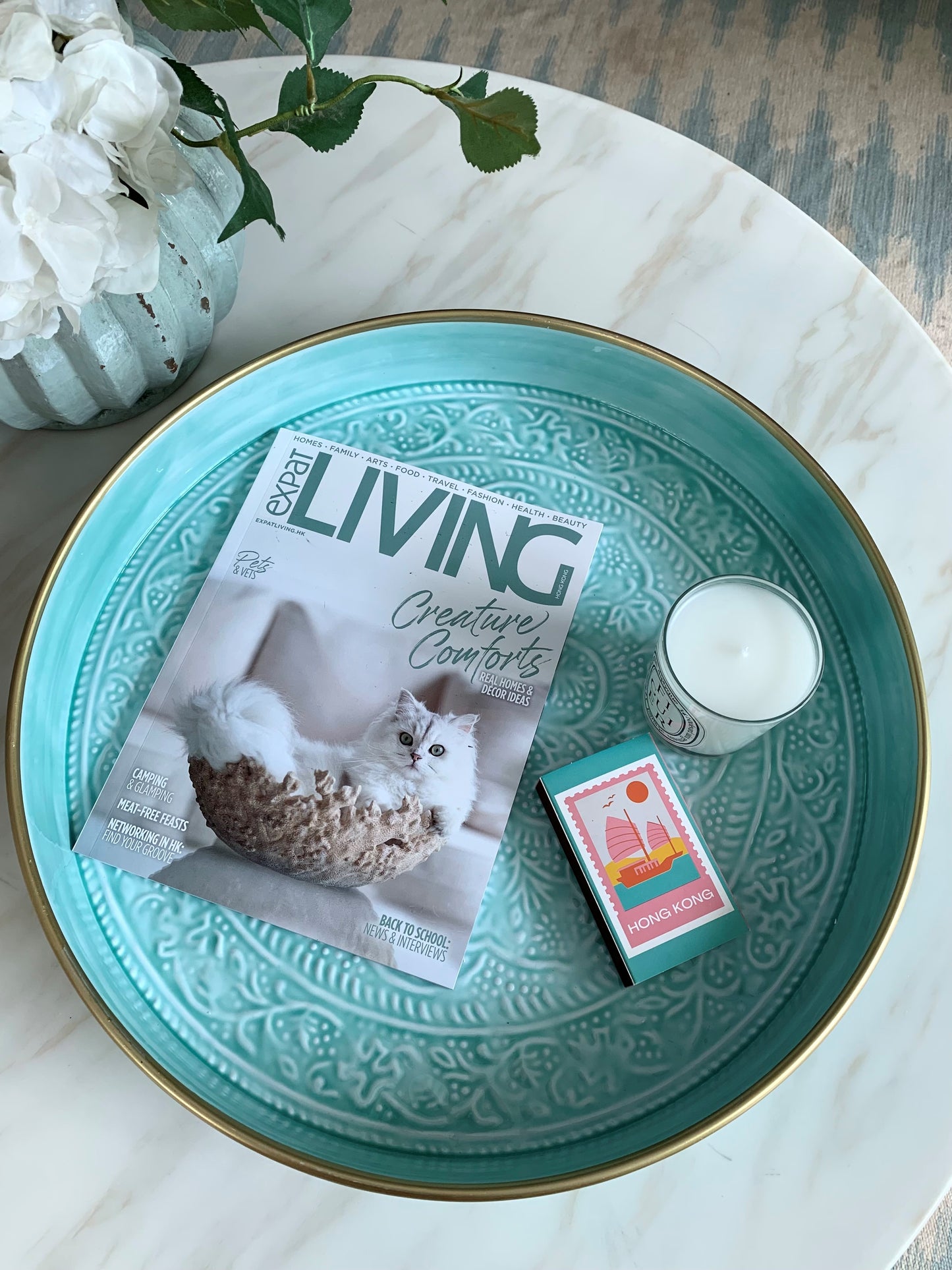 A large light blue tray on a coffee table with a magazine and candle on it.