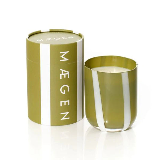 Mágen candle in a green glass container with a matching cylindrical box on a white background