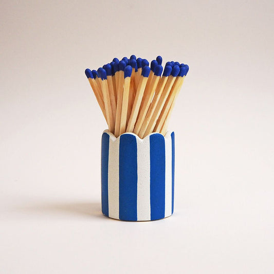 A striped blue matchstick pot with scalloped edges and long matches