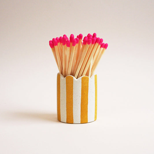 yellow striped matchstick pot with scalloped edges and long pink matches