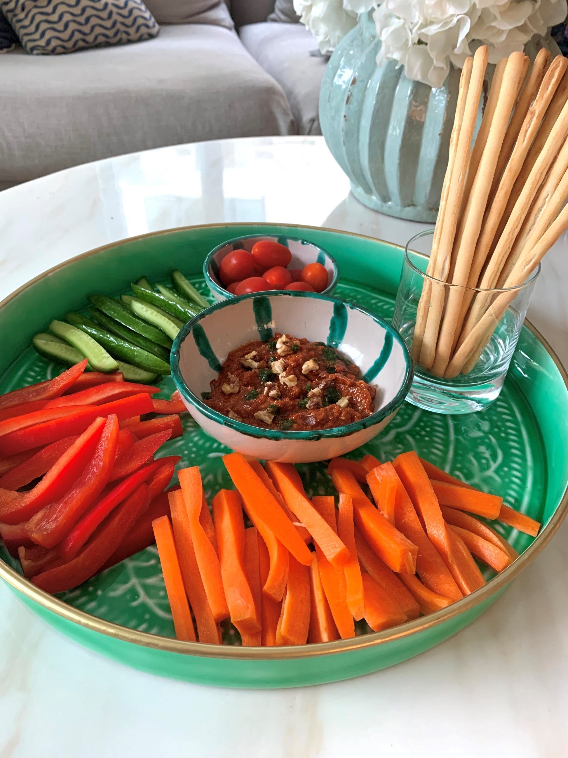 A green enamel tray displaying crudite and dip on a coffee table.