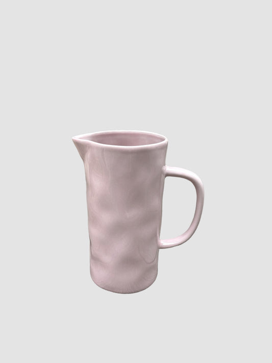 A medium sized handmade jug in a pale pink colour