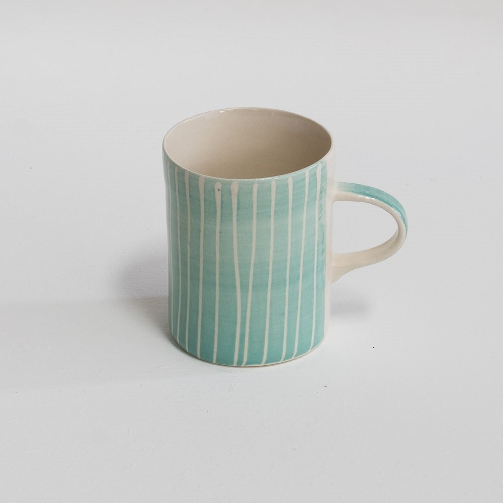 A mint coloured coffee mug with hand-painted white stripes.
