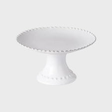 A white footed cake plate with beaded edging