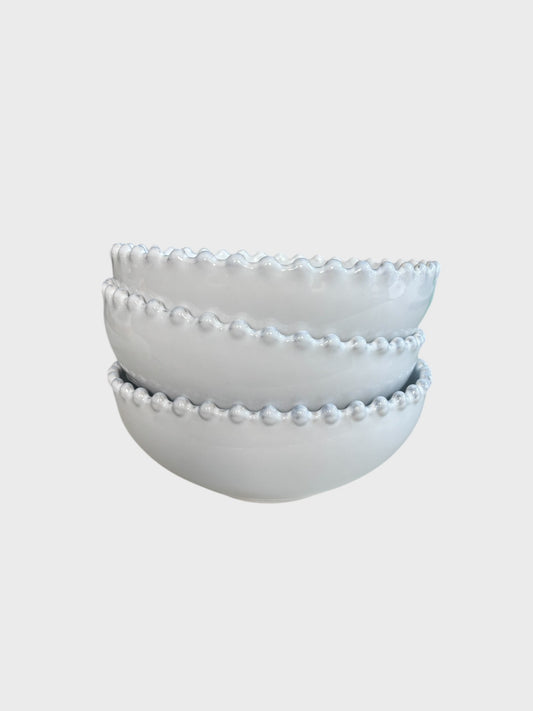 A stack of 3 white bowls with a beaded edge design