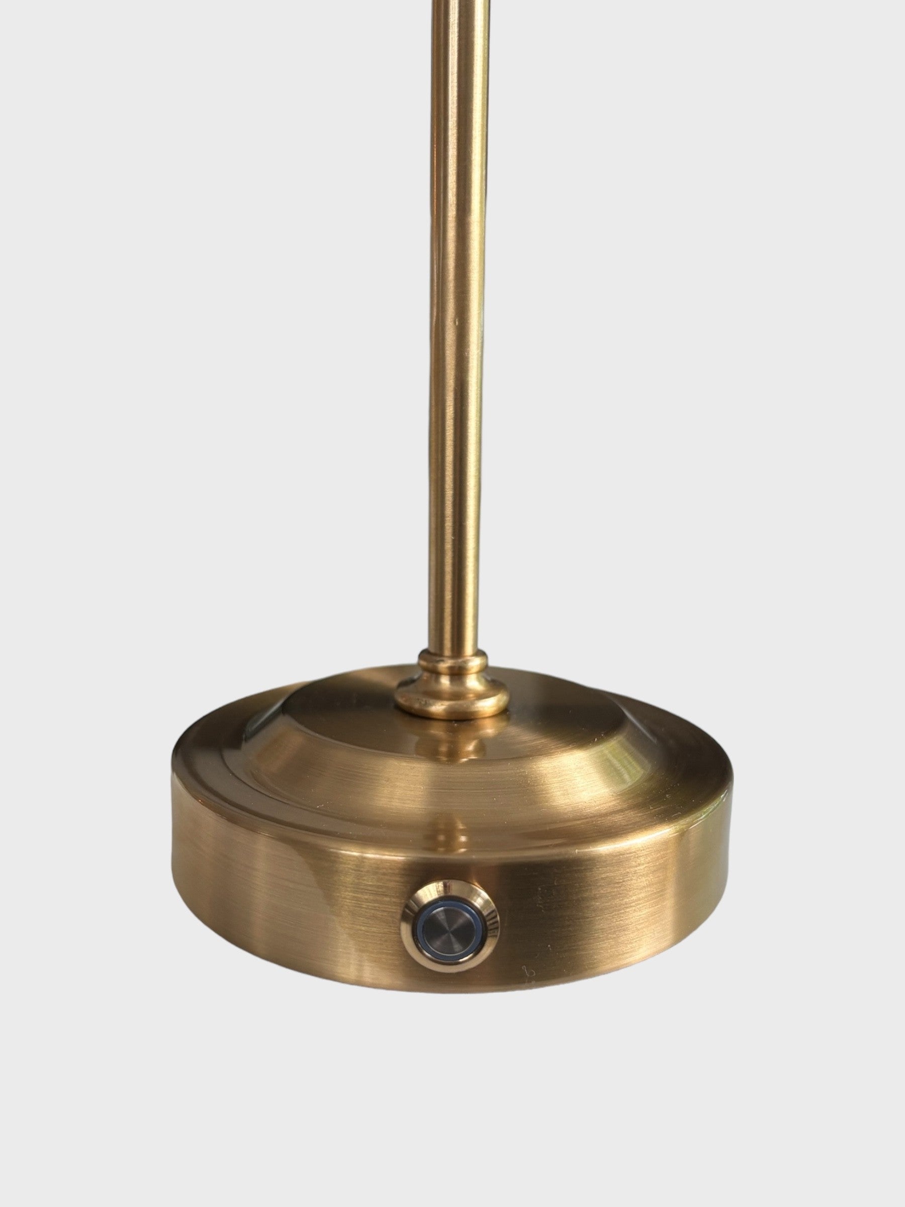 A close up of the brass finished lamp base of a rechargeable lamp showing the dimmer switch.