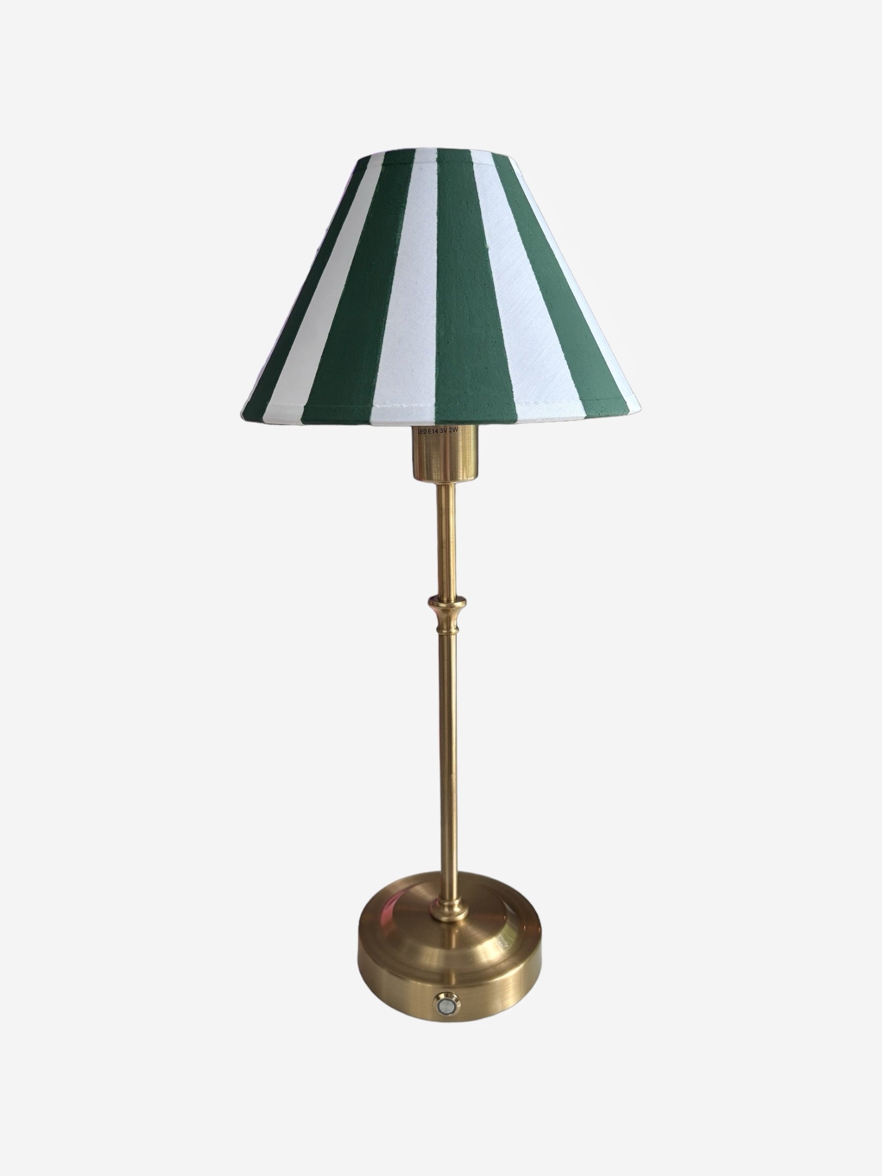 A rechargeable, cordless brass lamp with a hand painted green and white striped lampshade
