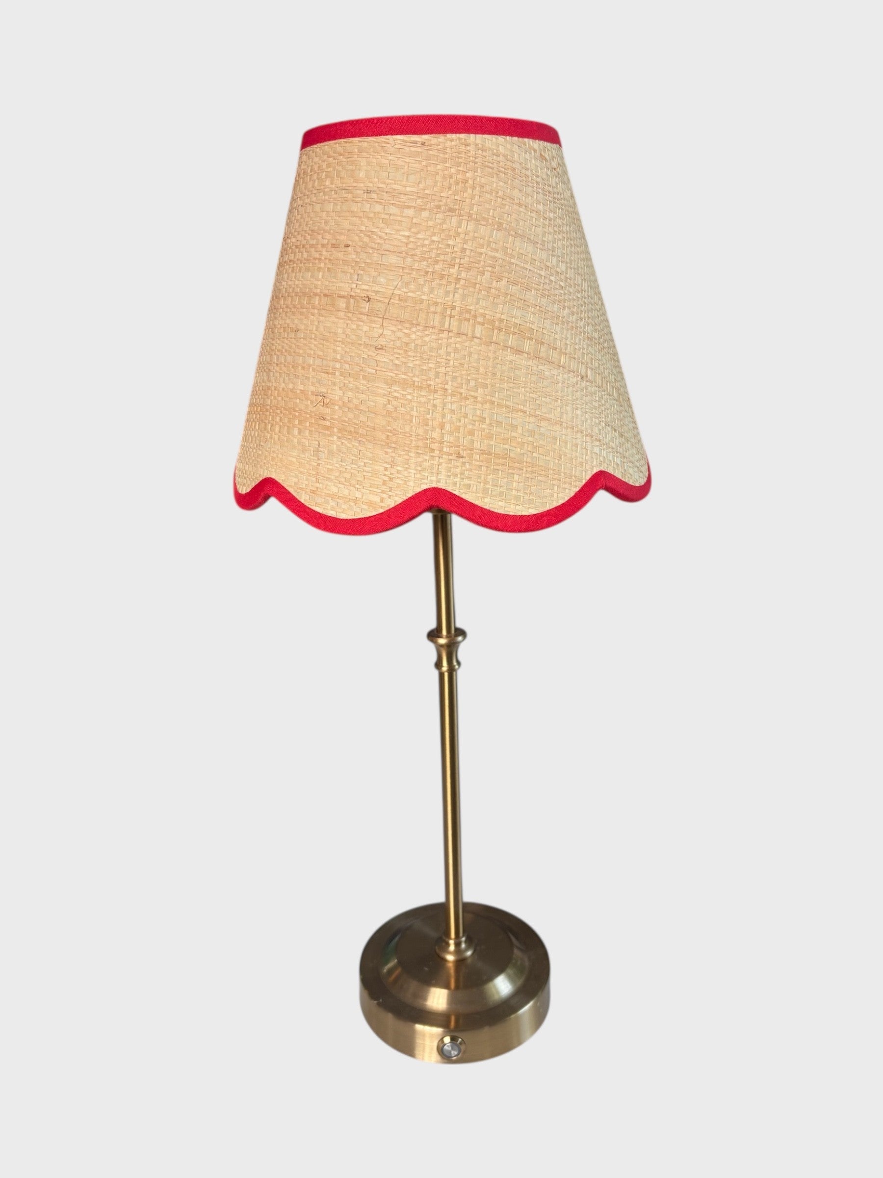Table lamp with a rattan lampshade and red scallop trim on a white background