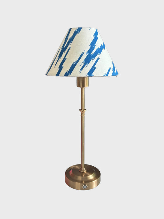 A cordless, rechargeable lamp with a handmade blue and white ikat shade.