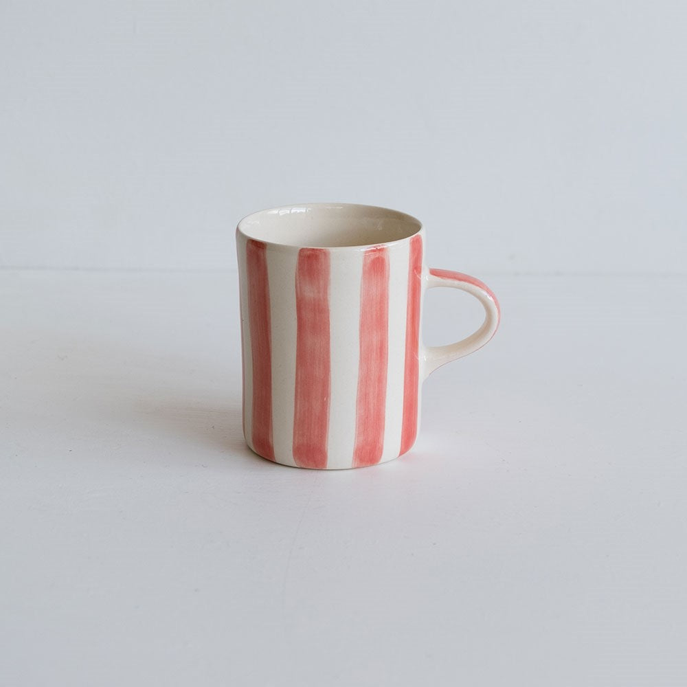 A coffee mug with hand-painted pink stripes.