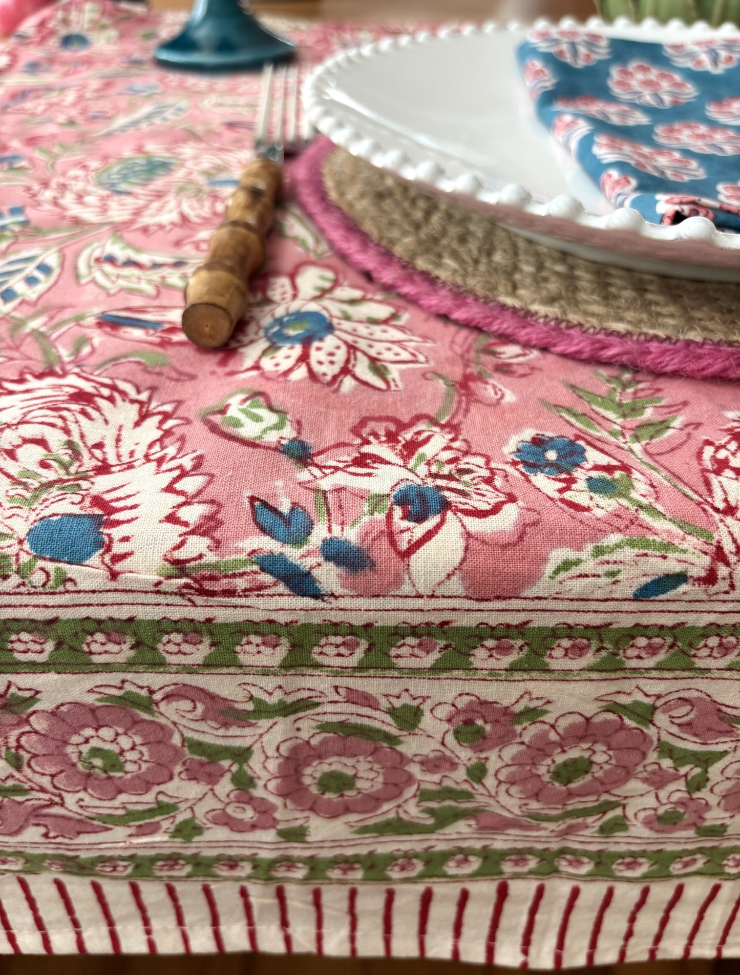 Floral-patterned tablecloth with a pink and green design on a table setting.