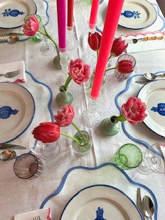 A Valentines table setting featuring pink tulips and pink, purple and red candles