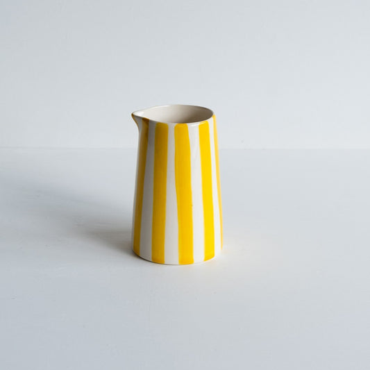 A yellow and white candy striped milk jug.  Handmade and hand-painted in Portugal.