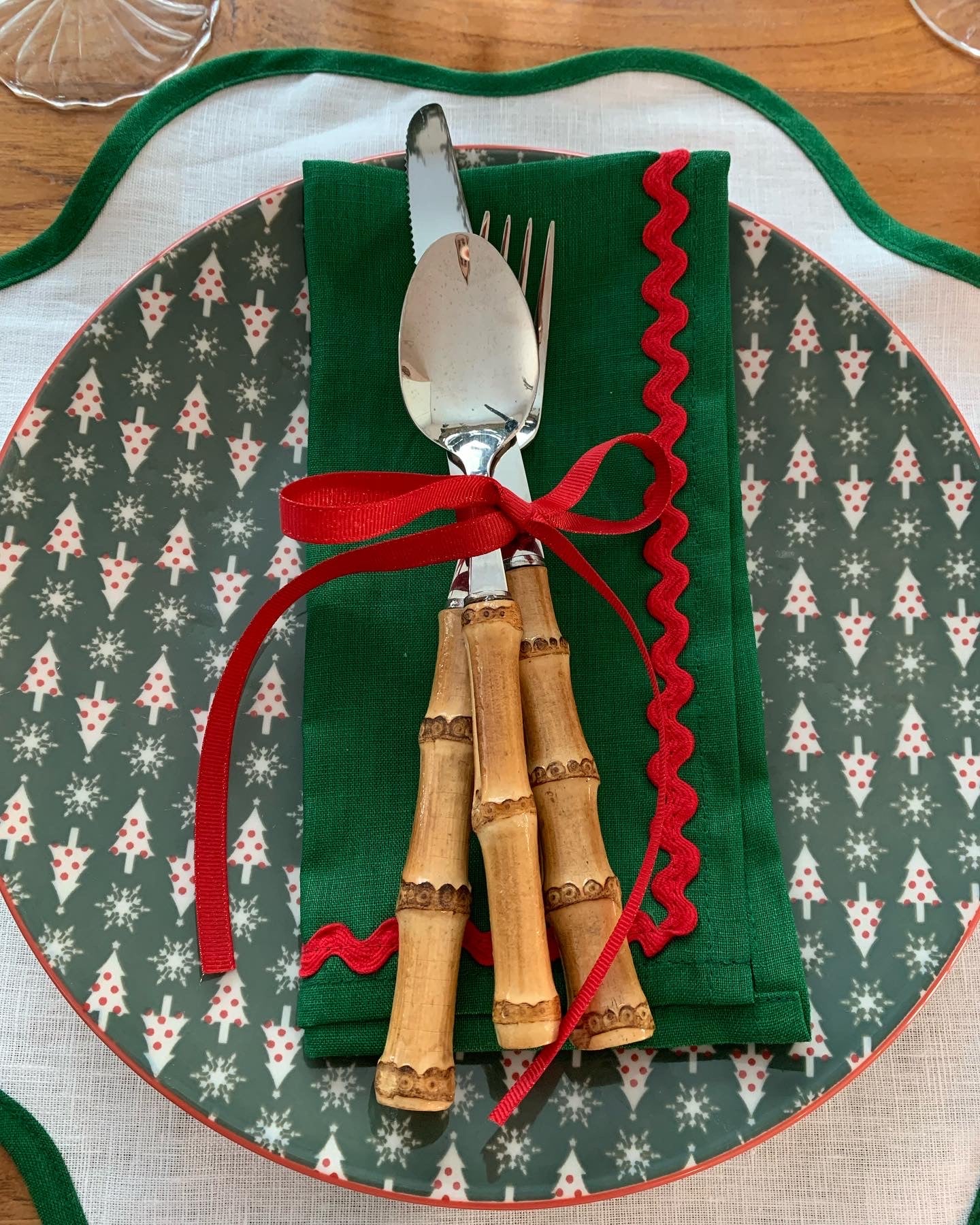 Bamboo cutlery tied with red ribbon set on a Christmas plate. 