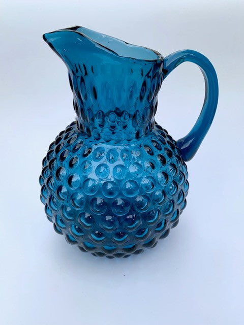 A dark blue hobnail glass jug.