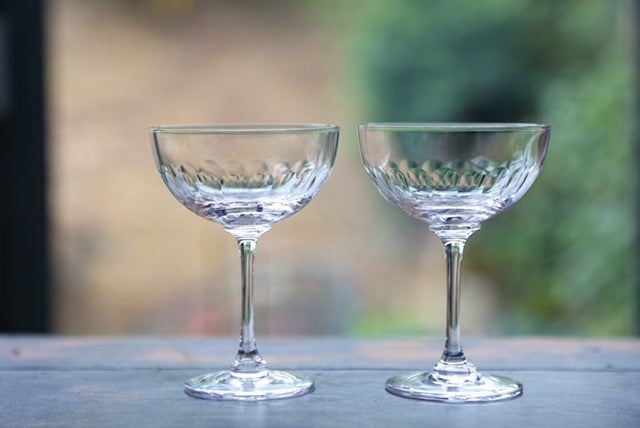 A pair of vintage inspired crystal champagne glasses with an engraved band of connecting ovals.