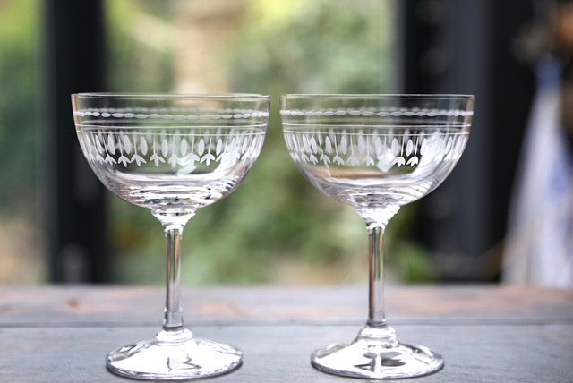 A pair of crystal champagne coupes with a hand-etched ovals motif.