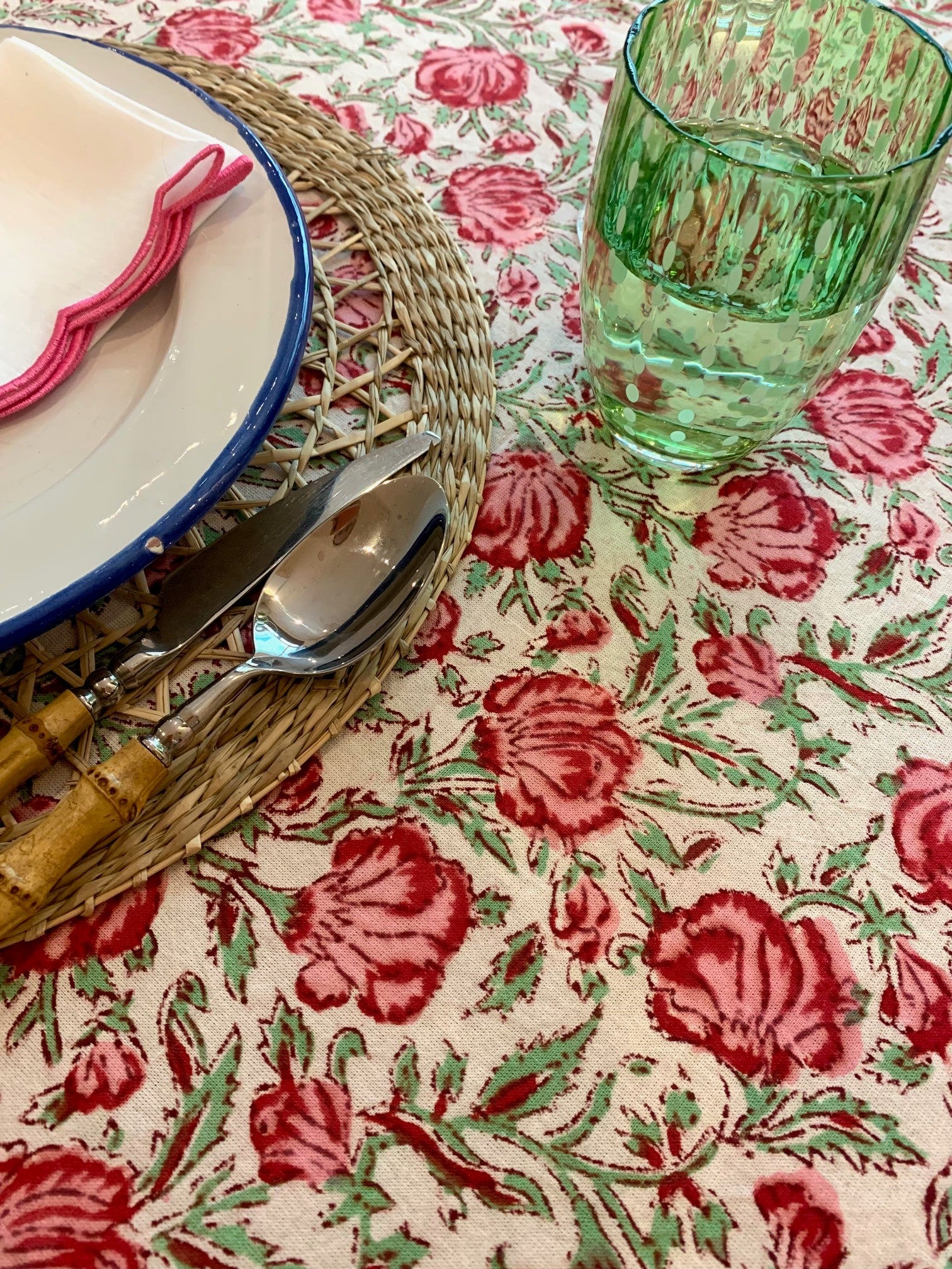 A green glass of water on a floral block print tablecloth 