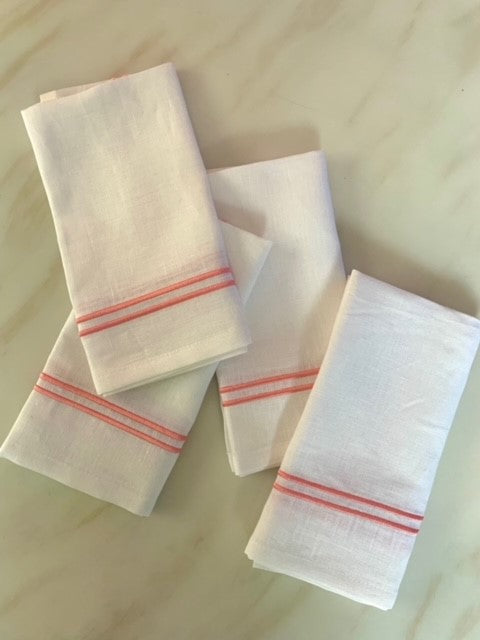 4 white linen napkins with double edged piping in coral