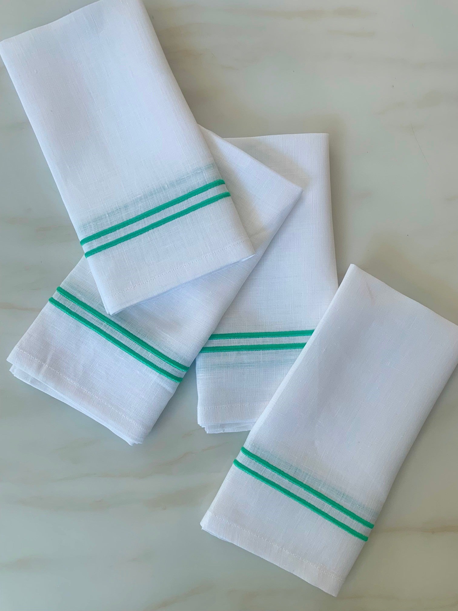 white linen napkins with double piping in green.
