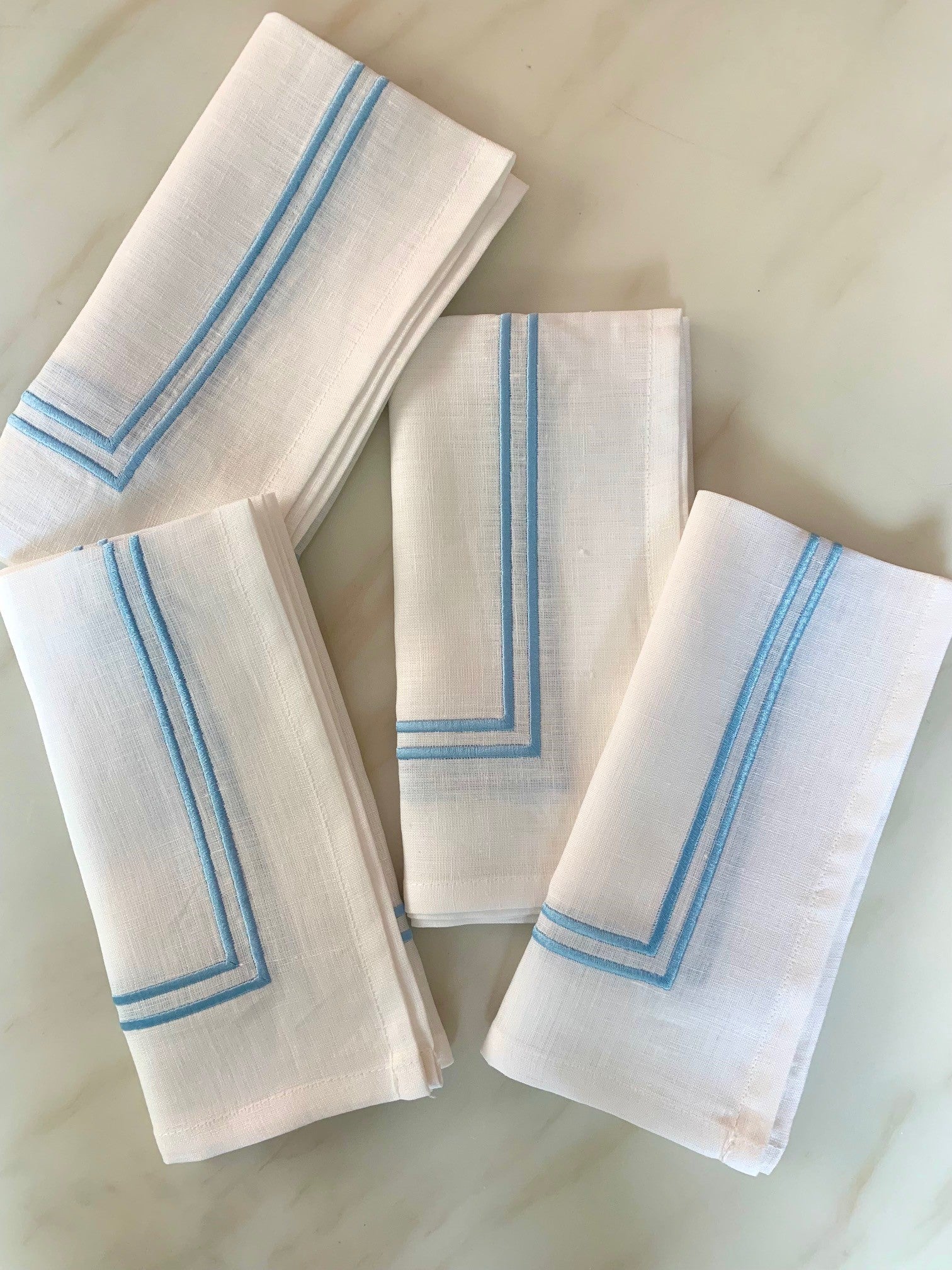 4 white linen napkins with double piped borders in sky blue