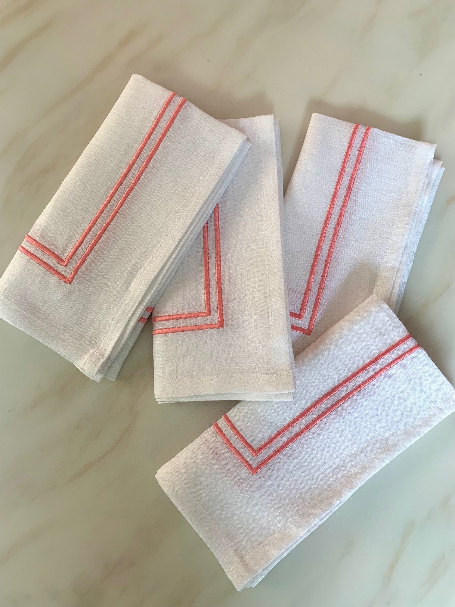4 white linen napkins with double edged piping in coral