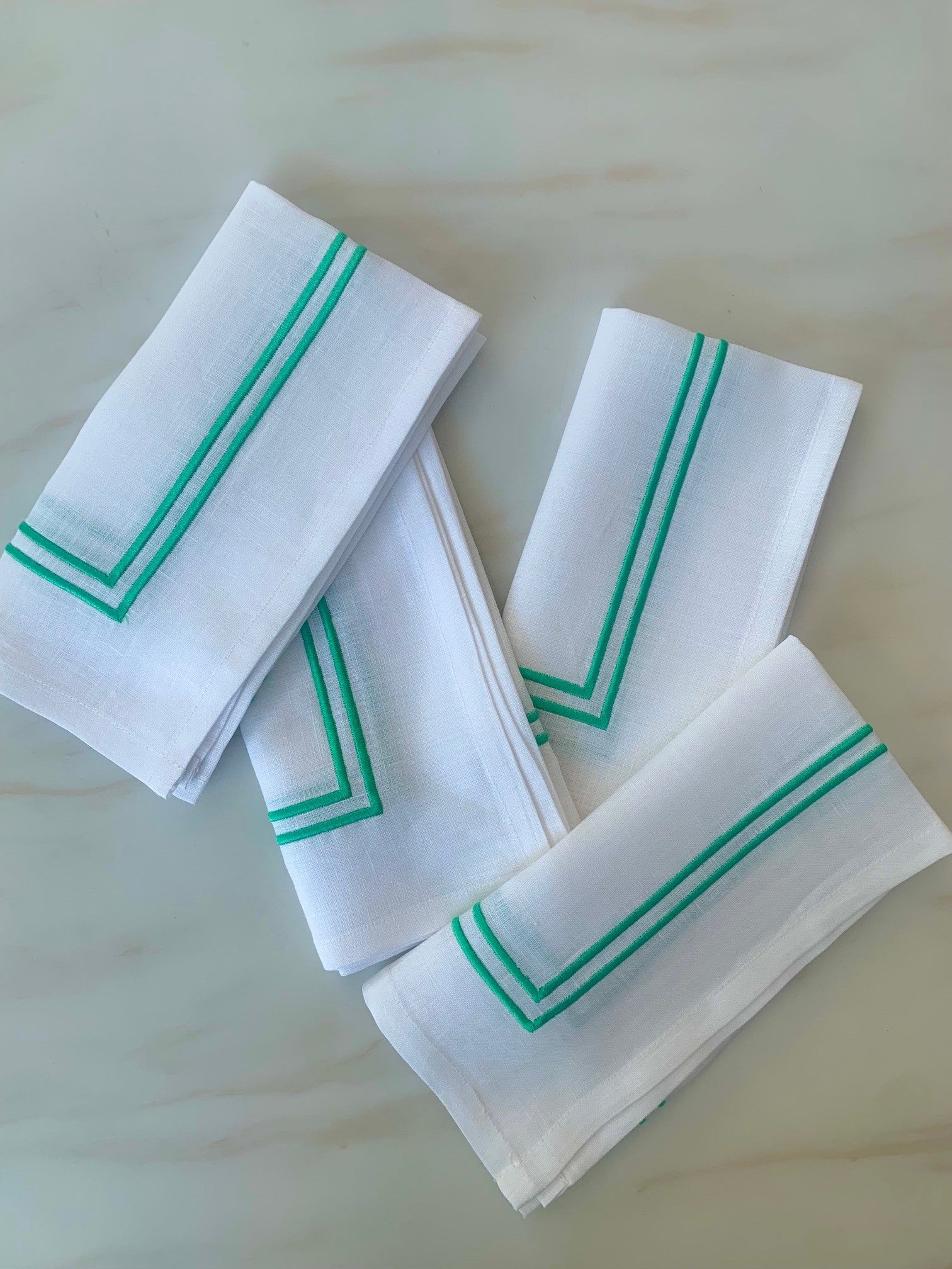 White linen napkins with green double piping