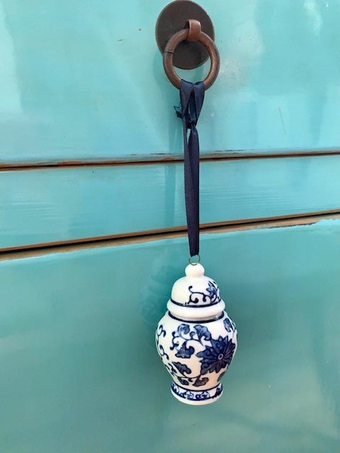 A mini blue and white ginger jar hanging from a drawer handle.